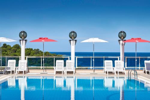 einen Pool mit Stühlen und Sonnenschirmen und das Meer in der Unterkunft Hotel Gran Vista Plava Laguna in Poreč