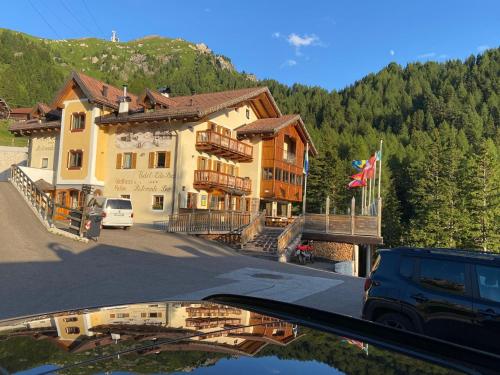 a car parked in front of a building with a mountain at Hotel Tita Piaz in Canazei