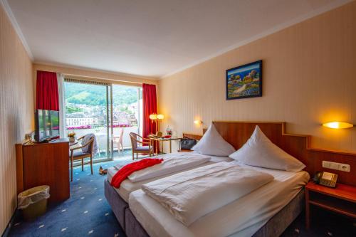 ein Hotelzimmer mit einem großen Bett und einem Balkon in der Unterkunft Moselstern Hotel Brixiade &Triton in Cochem