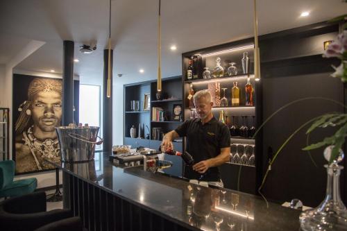 un homme debout à un comptoir dans un bar dans l'établissement Elite Hotel - Gay Men Only, à Sitges