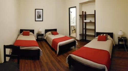 a room with three beds with red and white sheets at Hotel Naira in La Paz