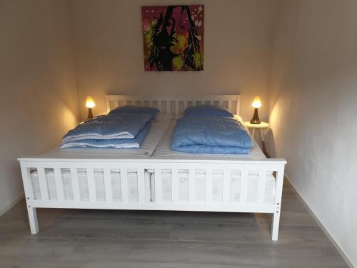 een wit bed met twee blauwe kussens erop bij Emda Country living close to Legoland in Billund