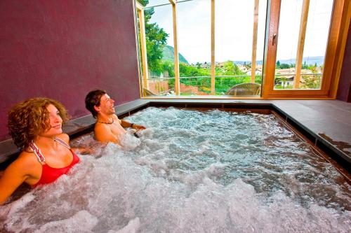 a man and a woman sitting in a hot tub at Hotel Goldener Stern in Caldaro