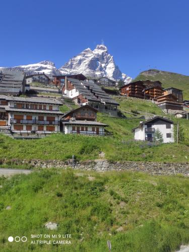 un grupo de edificios en una colina con una montaña en TANA DELLA MARMOTTA - renovated, ski in ski out, turkish bath, garage, storage, en Breuil-Cervinia