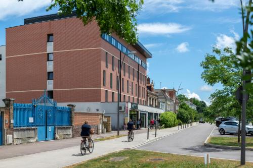 due persone in bicicletta lungo una strada cittadina di The Originals Residence, Kosy Appart'hotels Troyes City & Park a Troyes