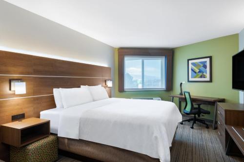 um quarto de hotel com uma grande cama branca e uma secretária em Holiday Inn Express & Suites Colorado Springs-Airport by IHG em Colorado Springs