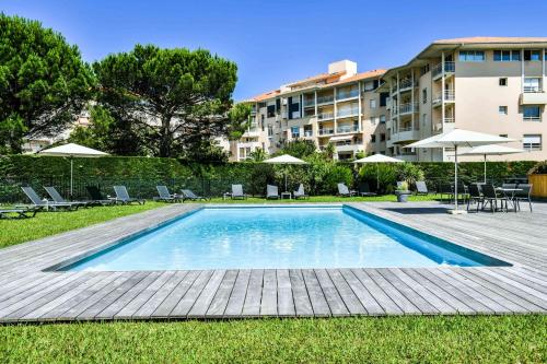 una piscina con sillas y sombrillas junto a un edificio en Hôtel Jules Verne Biarritz, en Biarritz