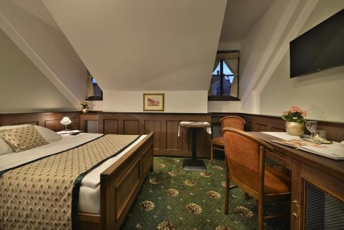 a bedroom with a bed and a desk and a television at Hotel Podhrad in Hluboká nad Vltavou