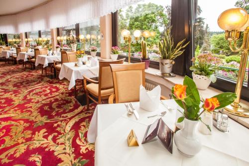 un restaurant avec des tables blanches, des chaises et des fenêtres dans l'établissement Hotel Hahnenkleer Hof, à Hahnenklee