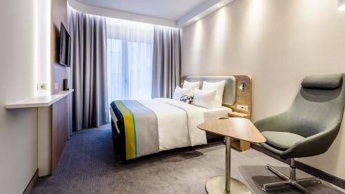 Pokój hotelowy z łóżkiem i krzesłem w obiekcie Holiday Inn Express - Rosenheim, an IHG Hotel w mieście Rosenheim