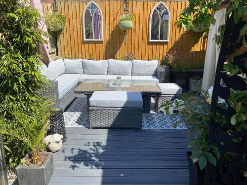 eine Terrasse mit einem weißen Sofa und einem Tisch in der Unterkunft Bournemouth 1 Bed Garden Flat Luxury Hot Tub in Bournemouth