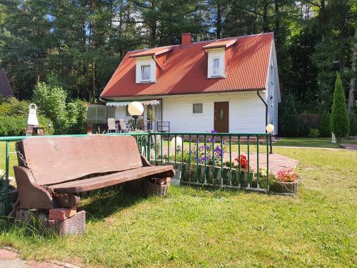 ein Haus mit rotem Dach und einer Bank im Gras in der Unterkunft Domek na Kaszubach in Bieszkowice