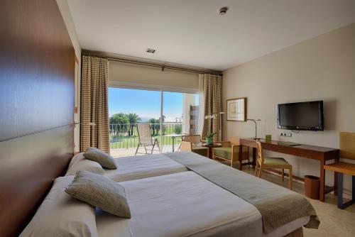 een slaapkamer met een bed, een bureau en een televisie bij Parador de Málaga Golf in Málaga