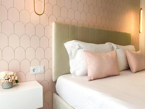 a bedroom with a bed with pink and white pillows at Batata - Estúdios in Nazaré