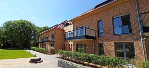 - un bâtiment en briques avec un balcon sur le côté dans l'établissement Wohnen am Südstrand - Ferienwohnung 1 2, à Wyk auf Föhr