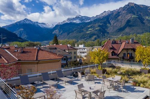 メラーノにあるResidence Villa Hedyの山々を背景にテーブルと椅子が備わるパティオ