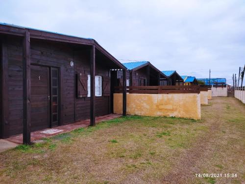 een houten gebouw met een hek naast een tuin bij Las Mozitas in Barra del Chuy