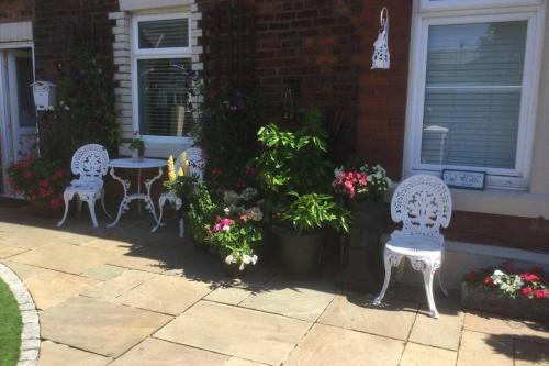 dwa białe krzesła i stół i kwiaty w obiekcie Leafy Lytham central Lovely ground floor 1 bedroom apartment with private garden In Lytham dog friendly w mieście Lytham St Annes