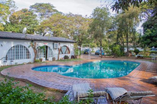 uma piscina com cadeiras e uma casa em The Ad Lib Executive lodge em Lilongwe