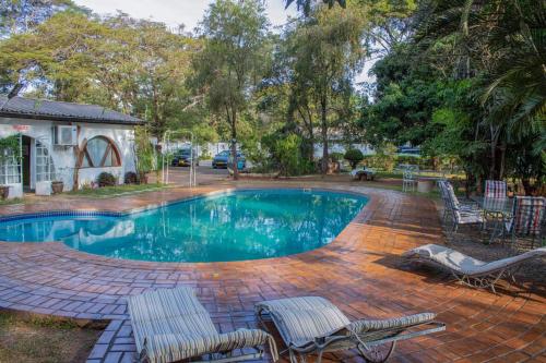 uma piscina com cadeiras e um pátio com uma mesa em The Ad Lib Executive lodge em Lilongwe