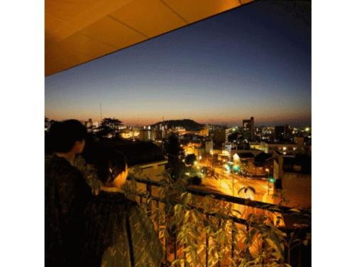 deux personnes qui regardent la ville la nuit dans l'établissement Dogo Onsen Funaya - Vacation STAY 54207v, à Matsuyama