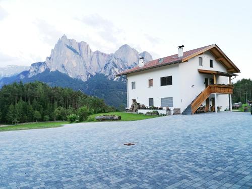 una casa con montagne sullo sfondo di Parlunkhof a Castelrotto