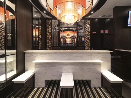 a lobby with a marble bar with benches and a chandelier at APA Hotel Shin Osaka Ekiminami in Osaka