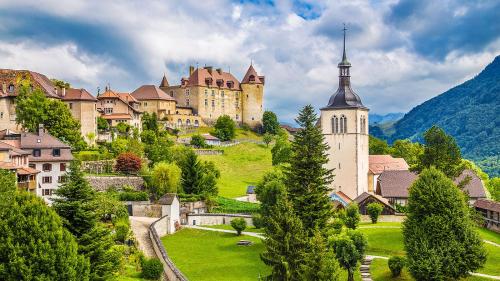 eine Stadt mit einem Schloss auf einem Hügel mit Bäumen in der Unterkunft Hôtel de Ville in Gruyères