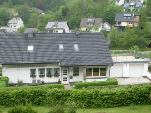 een wit huis met een grijs dak bij Ferienwohnung am Waldrand in Schmallenberg