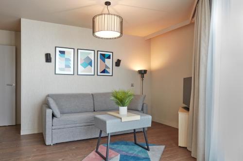 uma sala de estar com um sofá e uma mesa em Aparthotel Adagio Paris Suresnes Longchamp em Suresnes