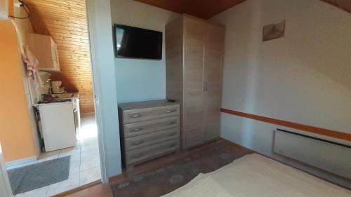 um pequeno quarto com uma cómoda e uma televisão em Pátri Apartmanház em Keszthely