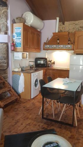 a kitchen with a table and a kitchen with a stove and refrigerator at A Paragűeria in Sas de Penelas