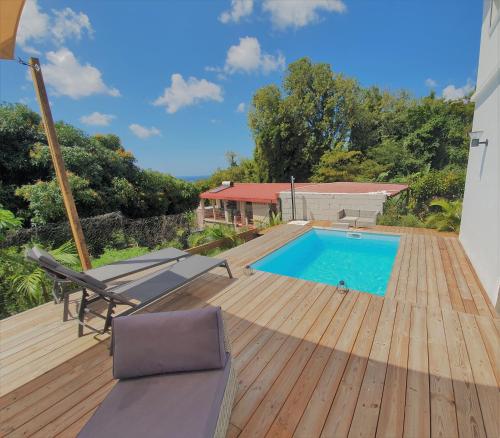 una terrazza in legno con piscina all'interno di una casa di Kozycoco - Suite Kozy - séjour tropical au calme a Schœlcher