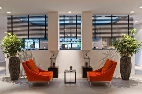 een lobby met 2 stoelen, een tafel en ramen bij Wyndham Stuttgart Airport Messe in Stuttgart