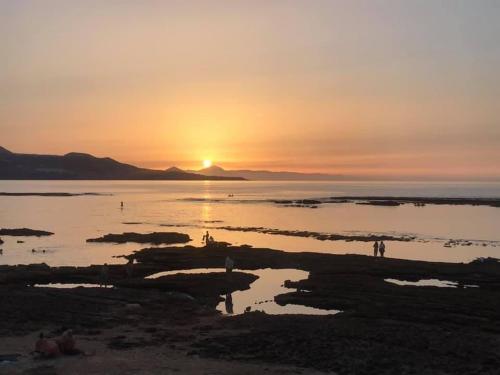 um pôr do sol sobre a água com pessoas na praia em Vista Teide 305-306 em Las Palmas de Gran Canárias