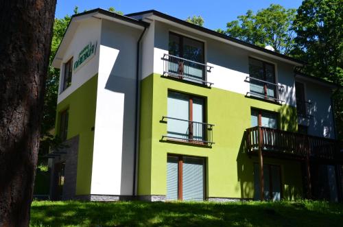 a yellow and white building with a tree at Penzión NADKA in Bojnice