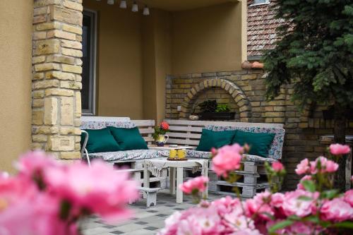 a patio with two benches and a table and flowers at Golden BIS, Subotica in Subotica