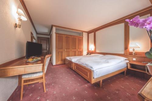 a bedroom with a bed and a desk with a computer at Antares Hotel in Zermatt