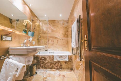 a bathroom with a sink and a tub and a toilet at Antares Hotel in Zermatt