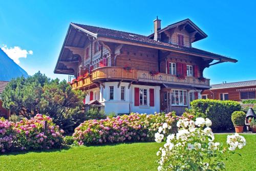 stary dom z kwiatami przed nim w obiekcie Chalet Maria Interlaken w mieście Interlaken