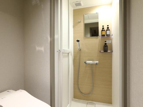 bagno con doccia, lavandino e specchio di Hotel Wing International Korakuen a Tokyo