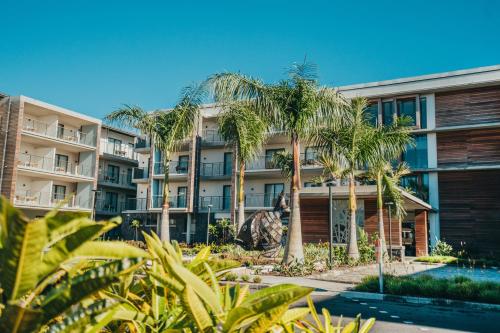 ein Apartmenthaus mit Palmen und einem Pool in der Unterkunft Domaine de Grand Baie in Grand Baie