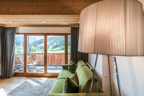 a living room with a green couch and a lamp at Ciasa Agreiter in La Villa