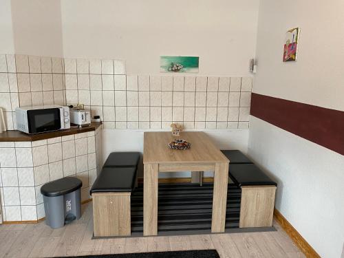 uma pequena cozinha com uma mesa e dois bancos em Ferienwohnung Eichhörnchen em Suhl