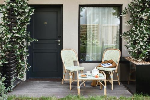 2 Stühle und ein Tisch auf einer Veranda mit einer Tür in der Unterkunft Hôtel Botaniste in Paris