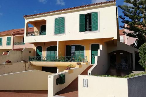 a large white building with green shutters at Beach House Villa At Peniche - Praia Consolação in Atouguia da Baleia