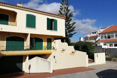 a white house with green shutters and a fence at Beach House Villa At Peniche - Praia Consolação in Atouguia da Baleia