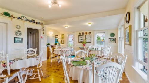 uma sala de jantar com mesas e cadeiras brancas em Bayview Pines Country Inn B&B em Mahone Bay