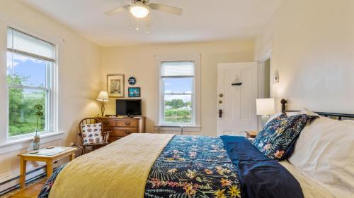 um quarto com uma cama, uma cómoda e 2 janelas em Bayview Pines Country Inn B&B em Mahone Bay