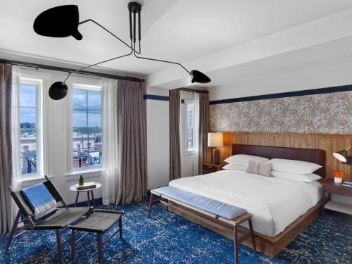 une chambre d'hôtel avec un lit et une chaise dans l'établissement Hotel Revival Baltimore, à Baltimore